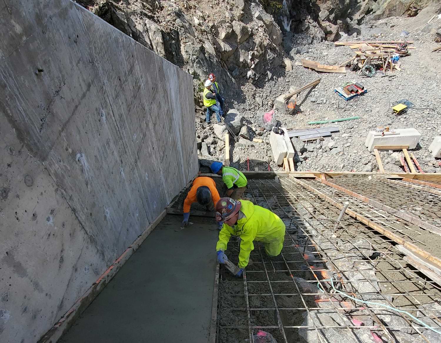 Orion crew members work on placing and finishing concrete on top of the 20-foot riprap spillway at the diversion site