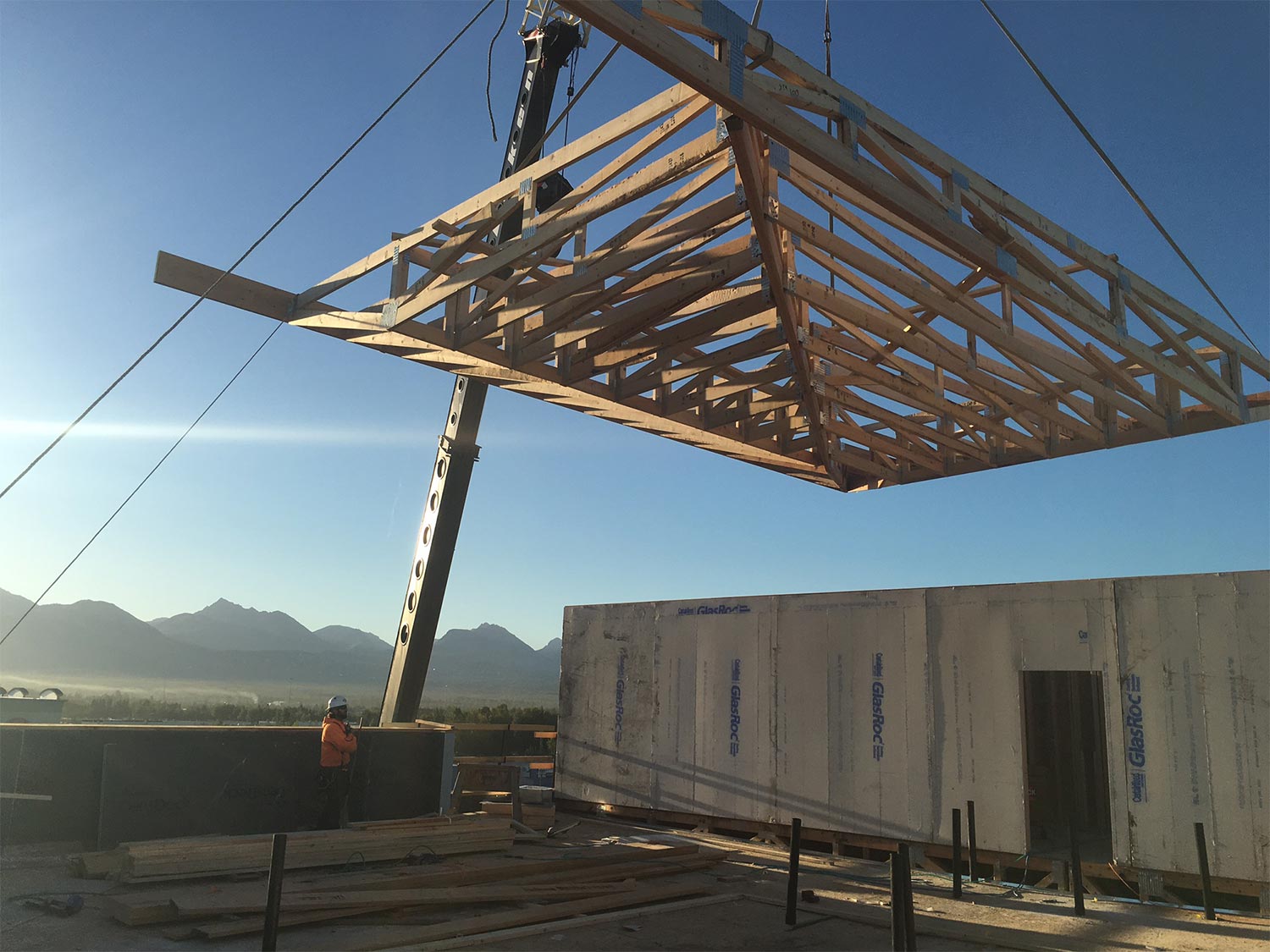 Loken Construction worker assisting crane position roof framing