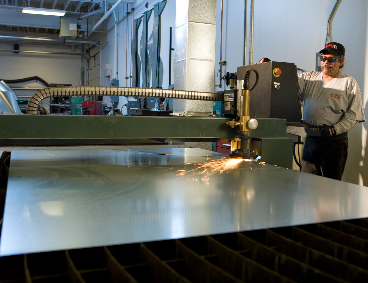 A KLEBS sheet metal shop fabricator operates an automated sheet metal cutting machine