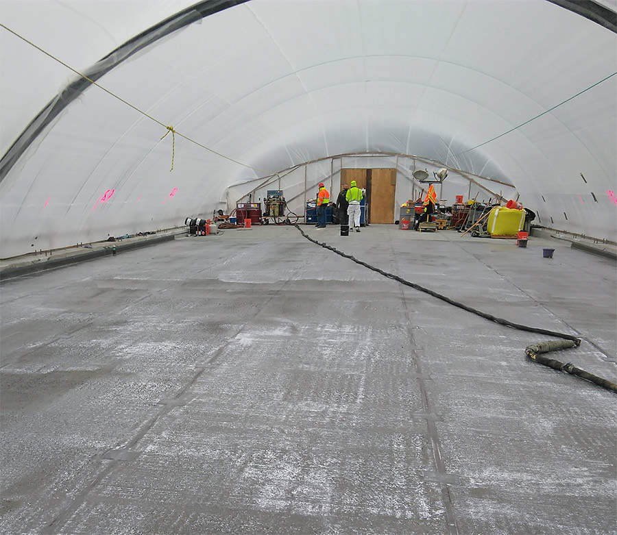Workers prime the Glacier Creek Bridge membrane inside a containment area on the Seward Highway