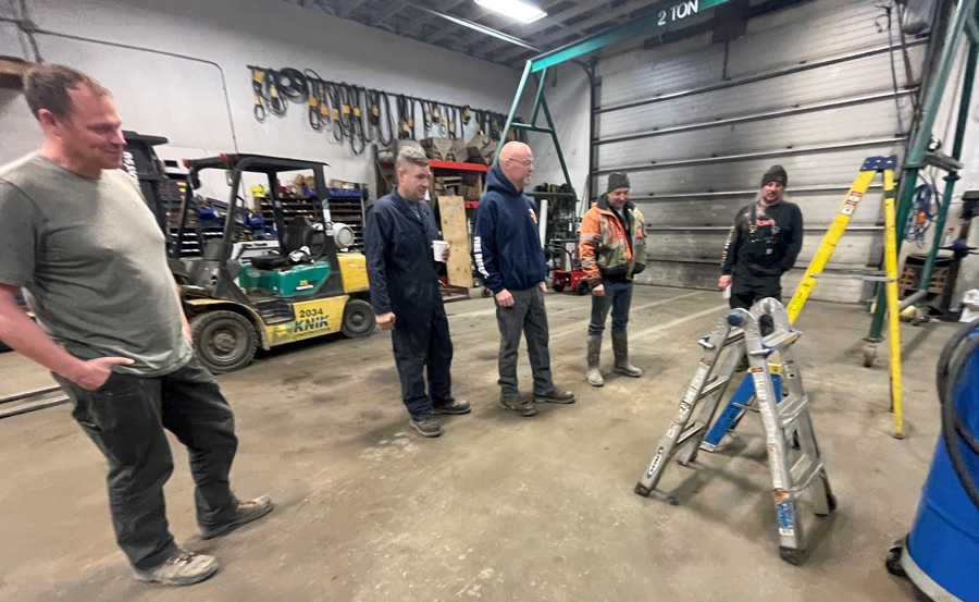 construction team in a warehouse comparing a tall ladder and a short ladder
