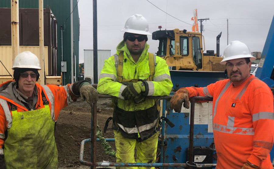 three construction workers pose for a picture while on the job