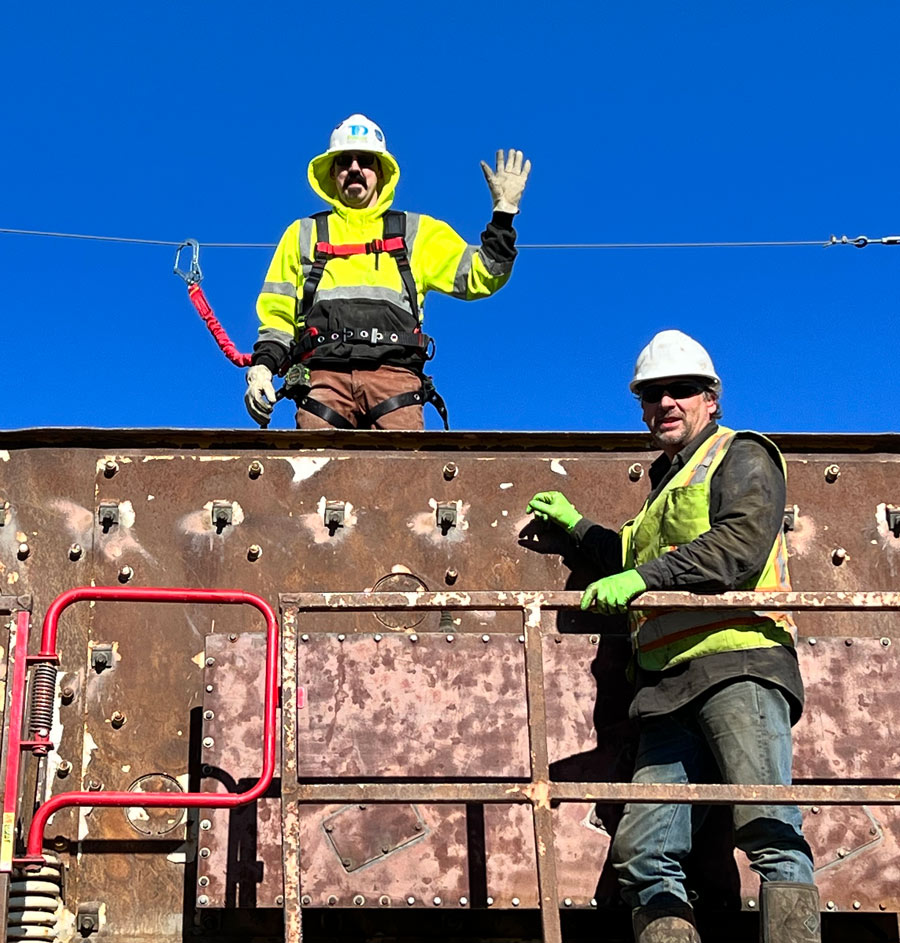 two construction workers waving to the camera while on the job