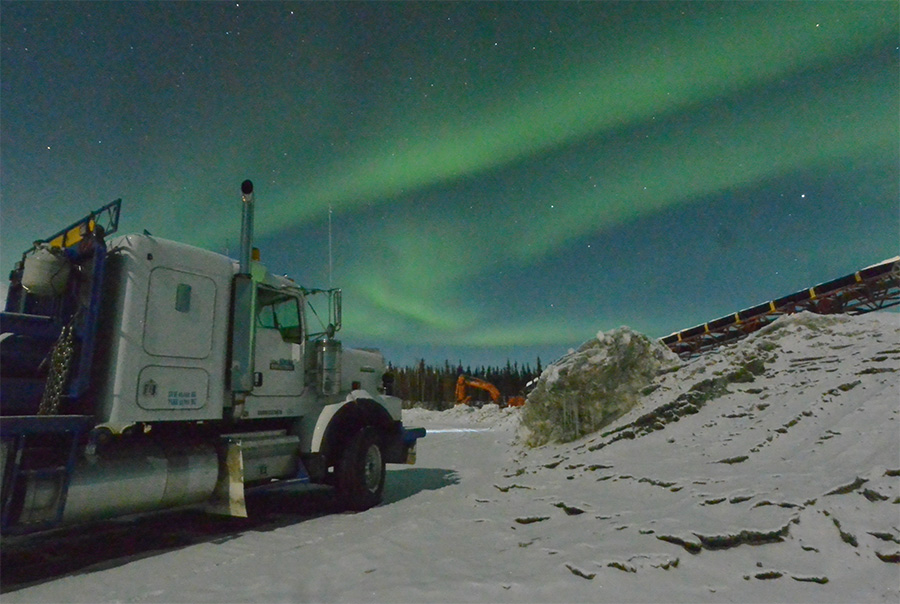 An Alaska Directional vehicle parked underneath an aurora borealis display along the Haul Road