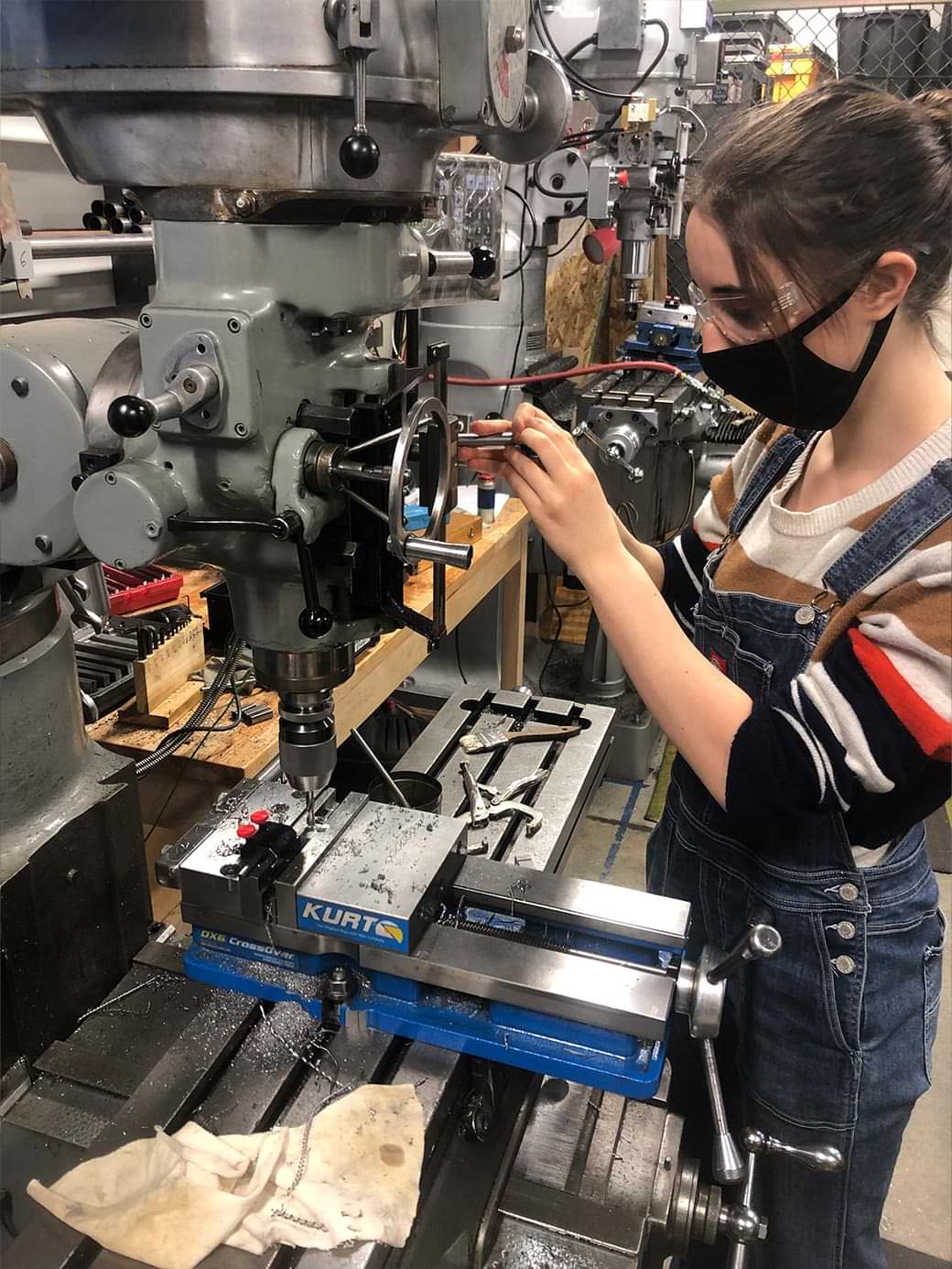 UAF engineering student Heather McKenzie machines a bridge component on a milling machine in a steel bridge shop
