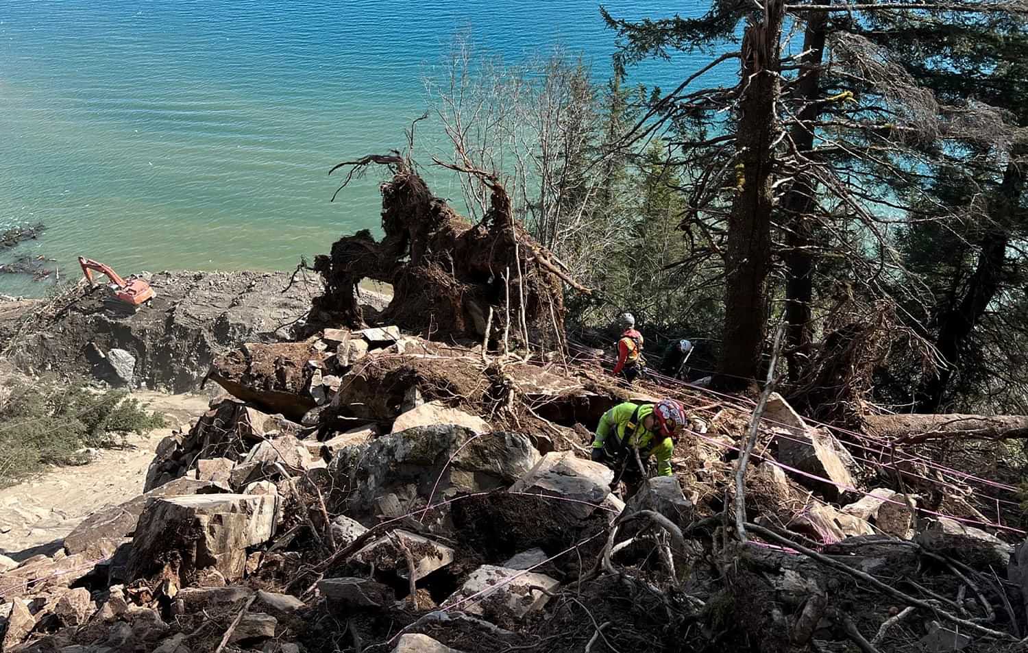 a clean up crew works on a landslide area over a body of water