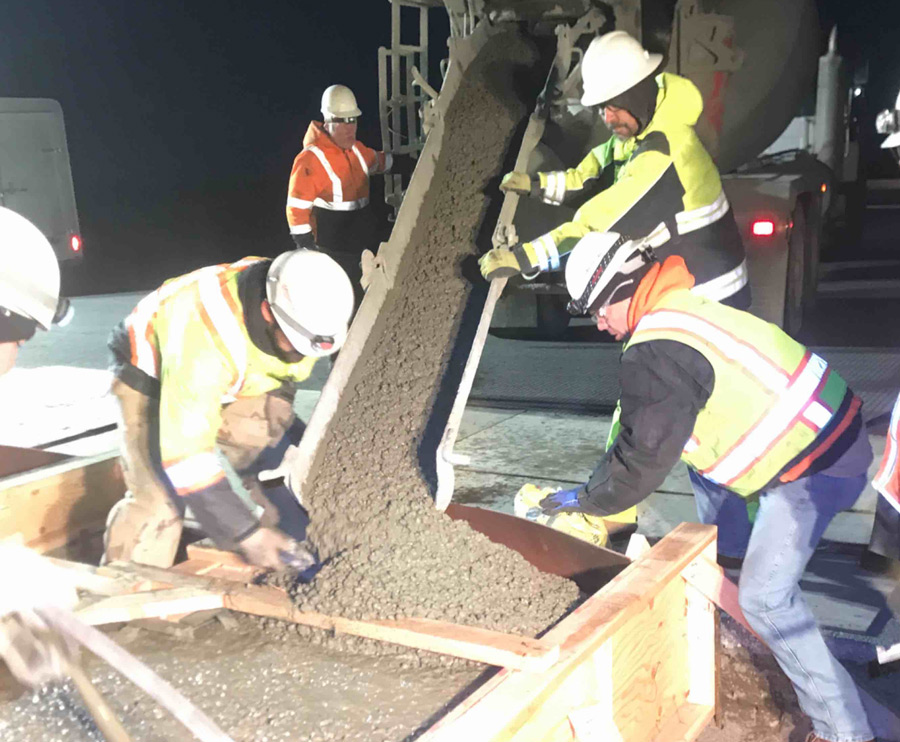 construction workers pouring concrete at night