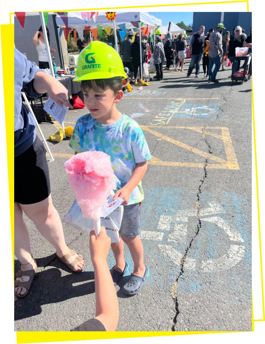 child with safety hat on with cotton candy in hands