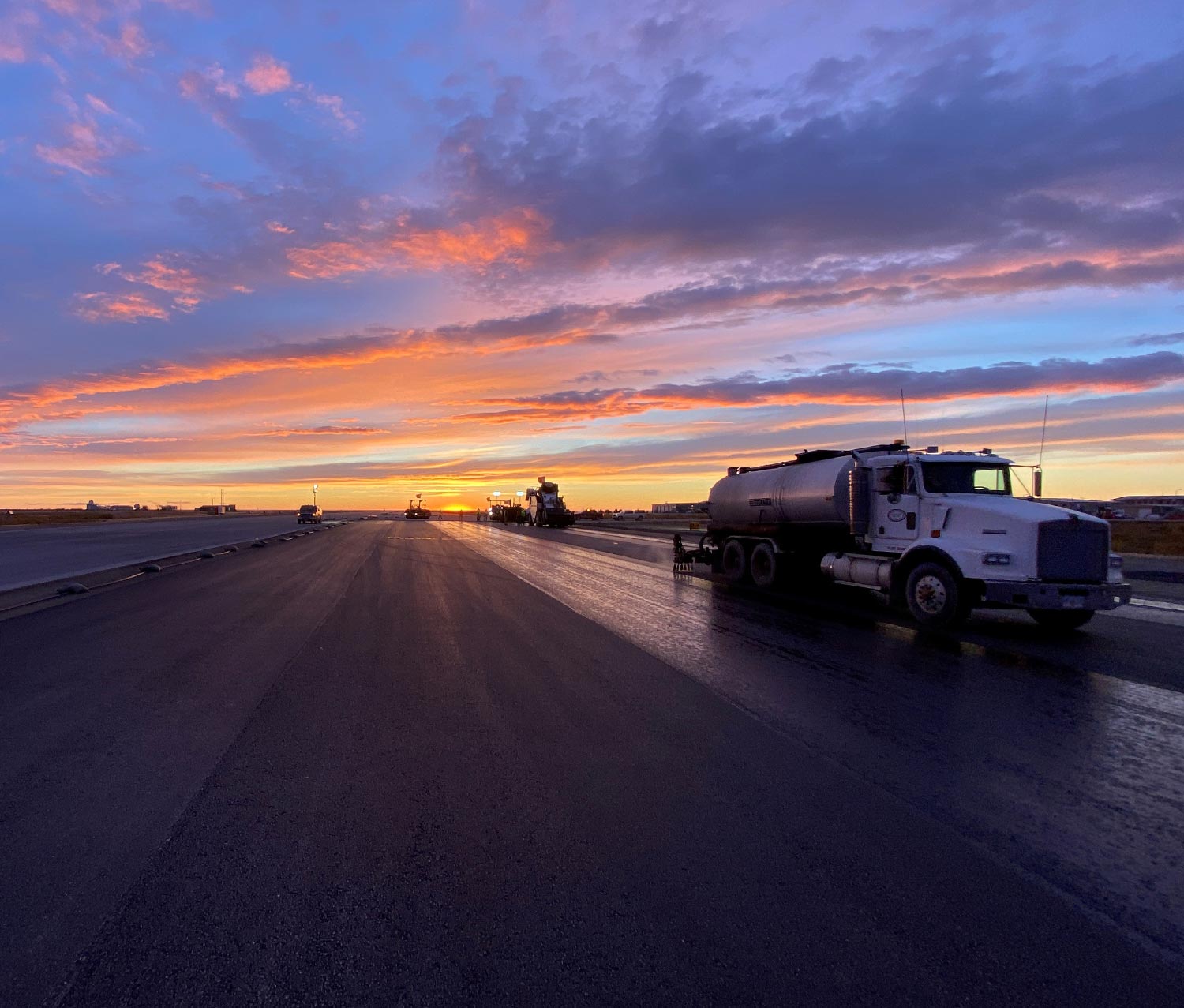 a work truck drives down an open road at dusk