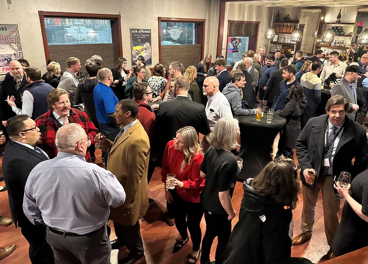 high angle view of a large bar room full of attendees holding refreshments and mingling at the 2023 AGC Alaska Legislative Fly-In event