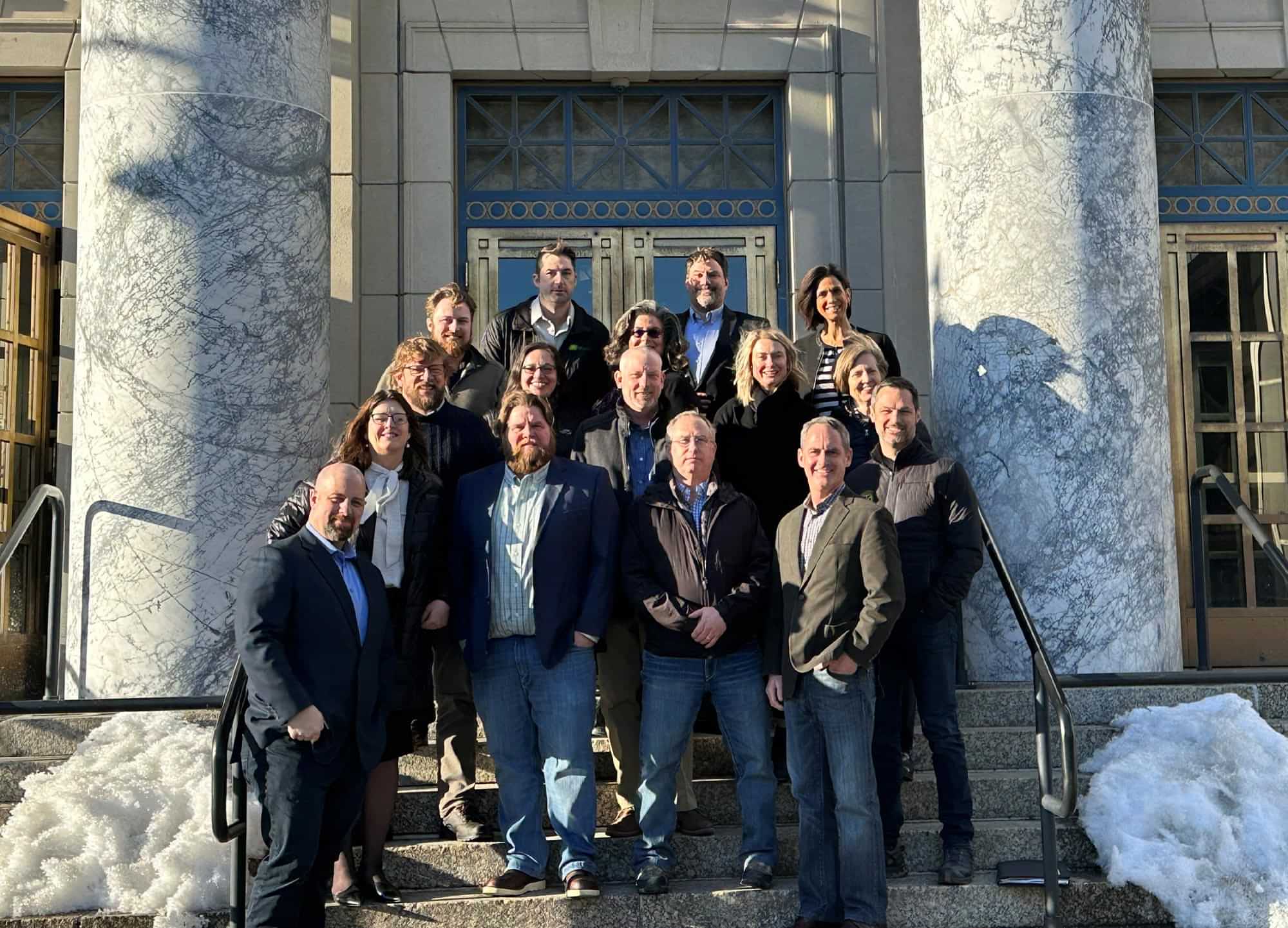 attendees of the 2023 AGC Alaska Legislative Fly-In event take a group photo on the entrance steps of a large pillared building