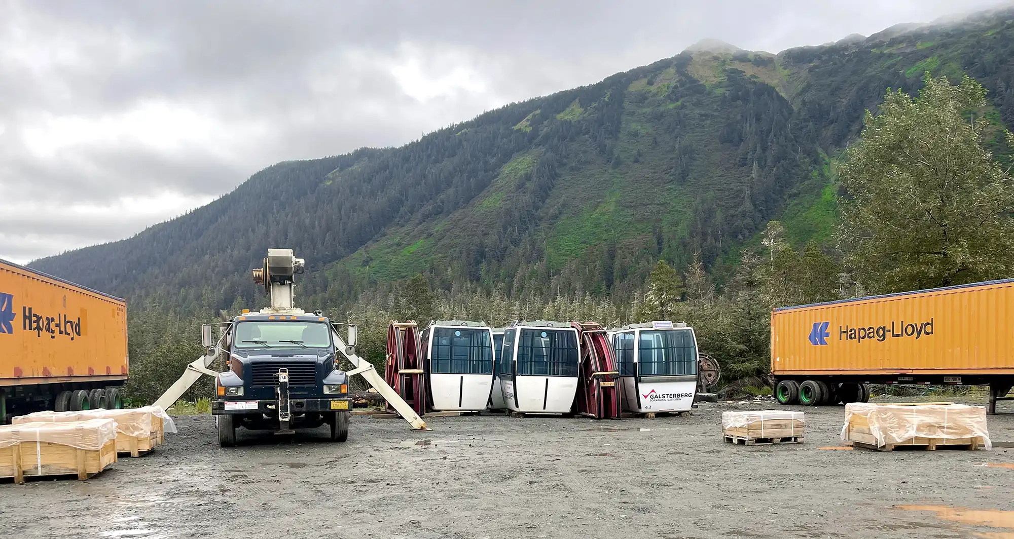 Semi trailers, boom truck and gondola cabins in lot
