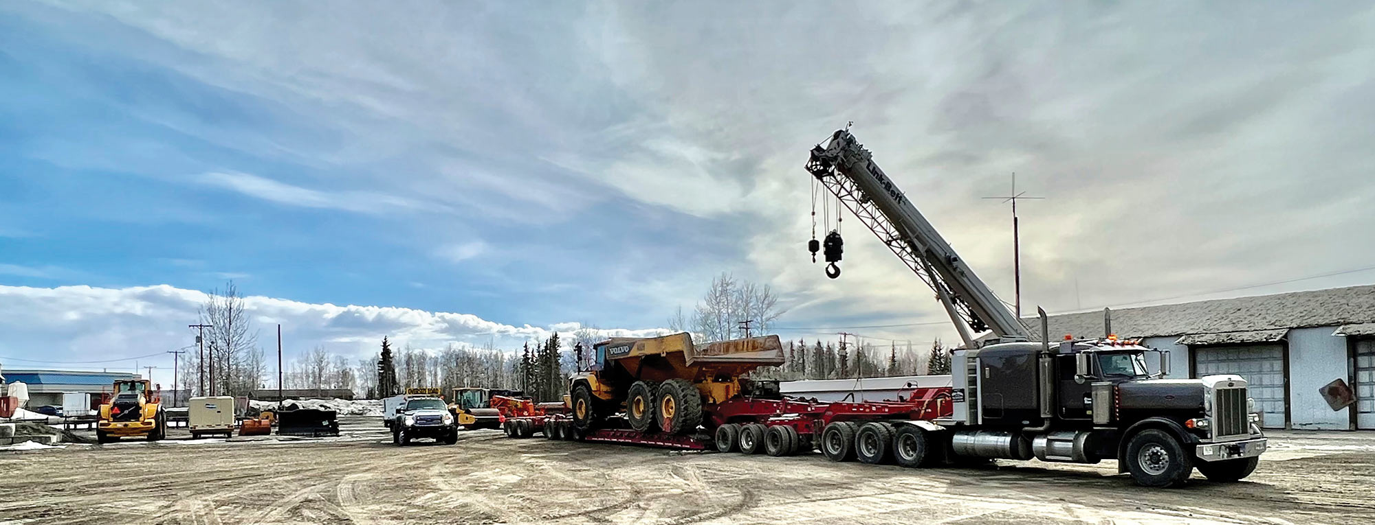 Tri axle Peterbuilt with long gooseneck trailer hauling a Volvo dump truck
