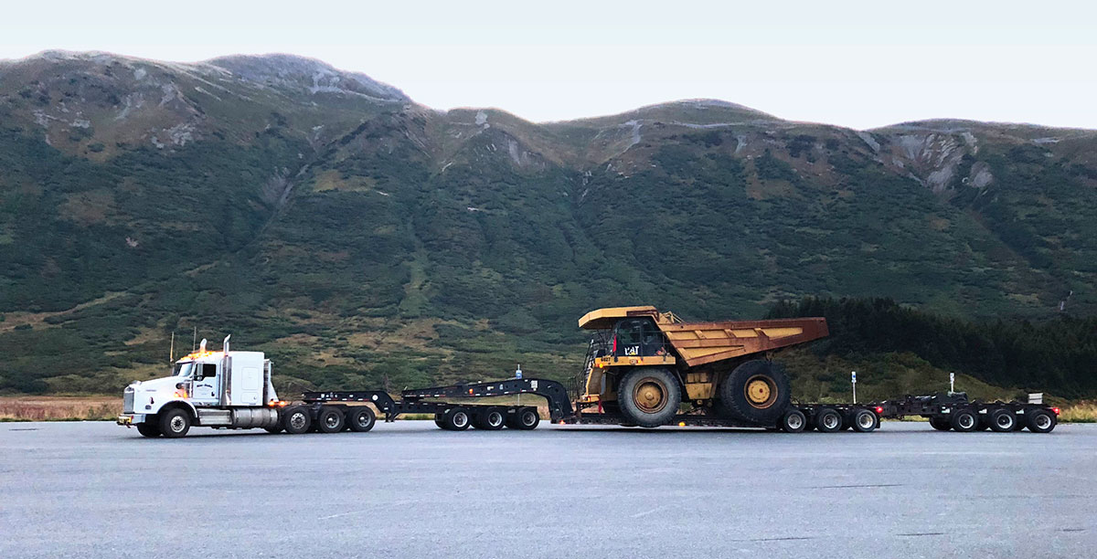 Tri axle truck hauling a Caterpillar mining truck