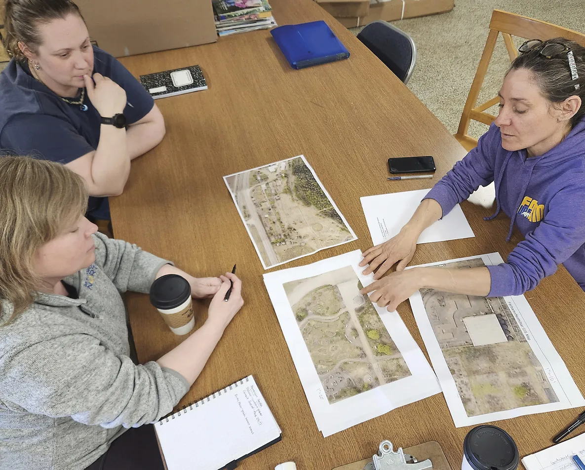 Landscape architect Stephanie Cloud, at bottom left, reviews design options for summer projects with Lacy Higham, top left, and Katie DiCristina, at right, both of UAF’s Georgeson Botanical Garden.