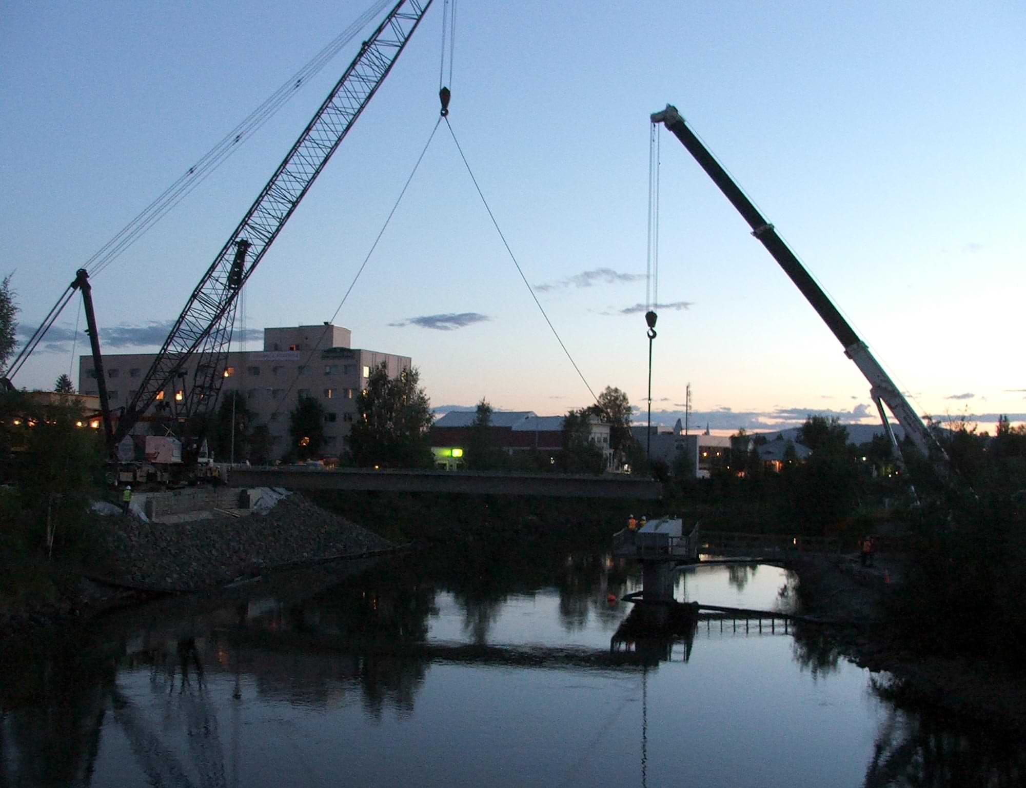 Precision Cranes and constructors work on the 2011 Cushman Street Bridge Project against a low sun