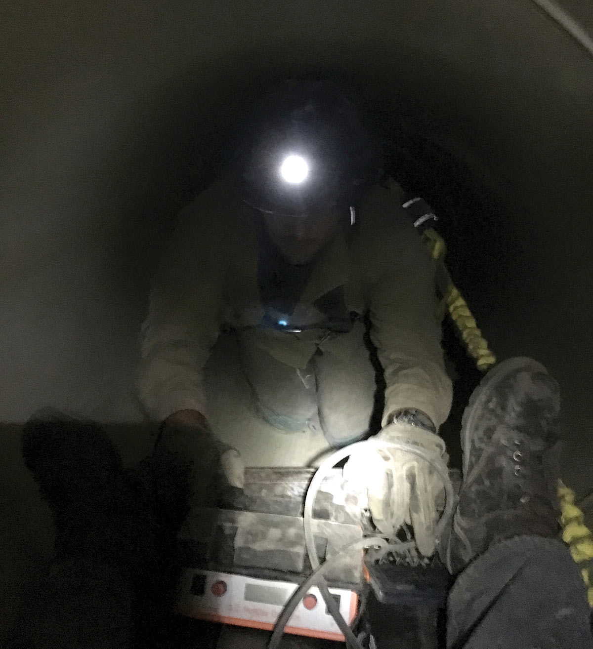 Jonathan Martin and Christian Mitchey lower equipment into the Allison Creek underground pipeline