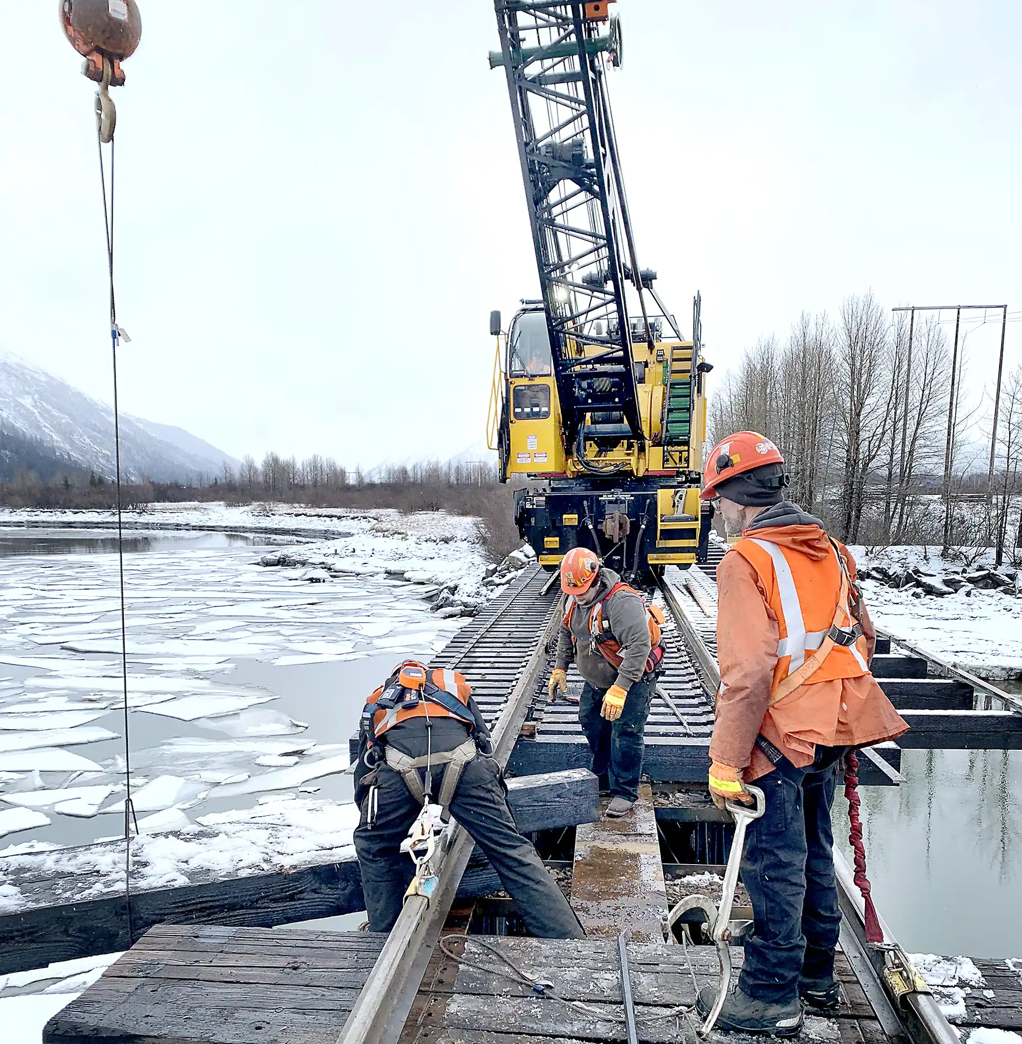 Workers replacing wood crossbeams on a bridge