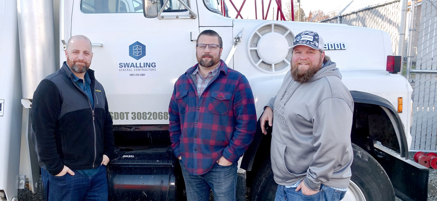 three partners that operate Swalling General Contractors stand together in front of a Swalling freight truck