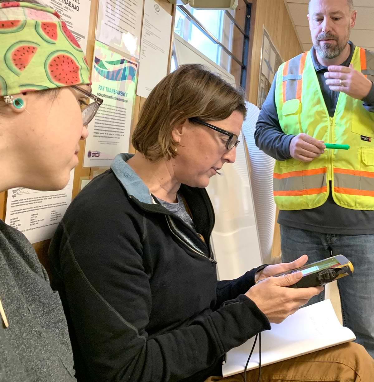 teachers Molly Suoja and Jenne Denton sit as QAP area manager Kris Jensen shows how technology is used in construction