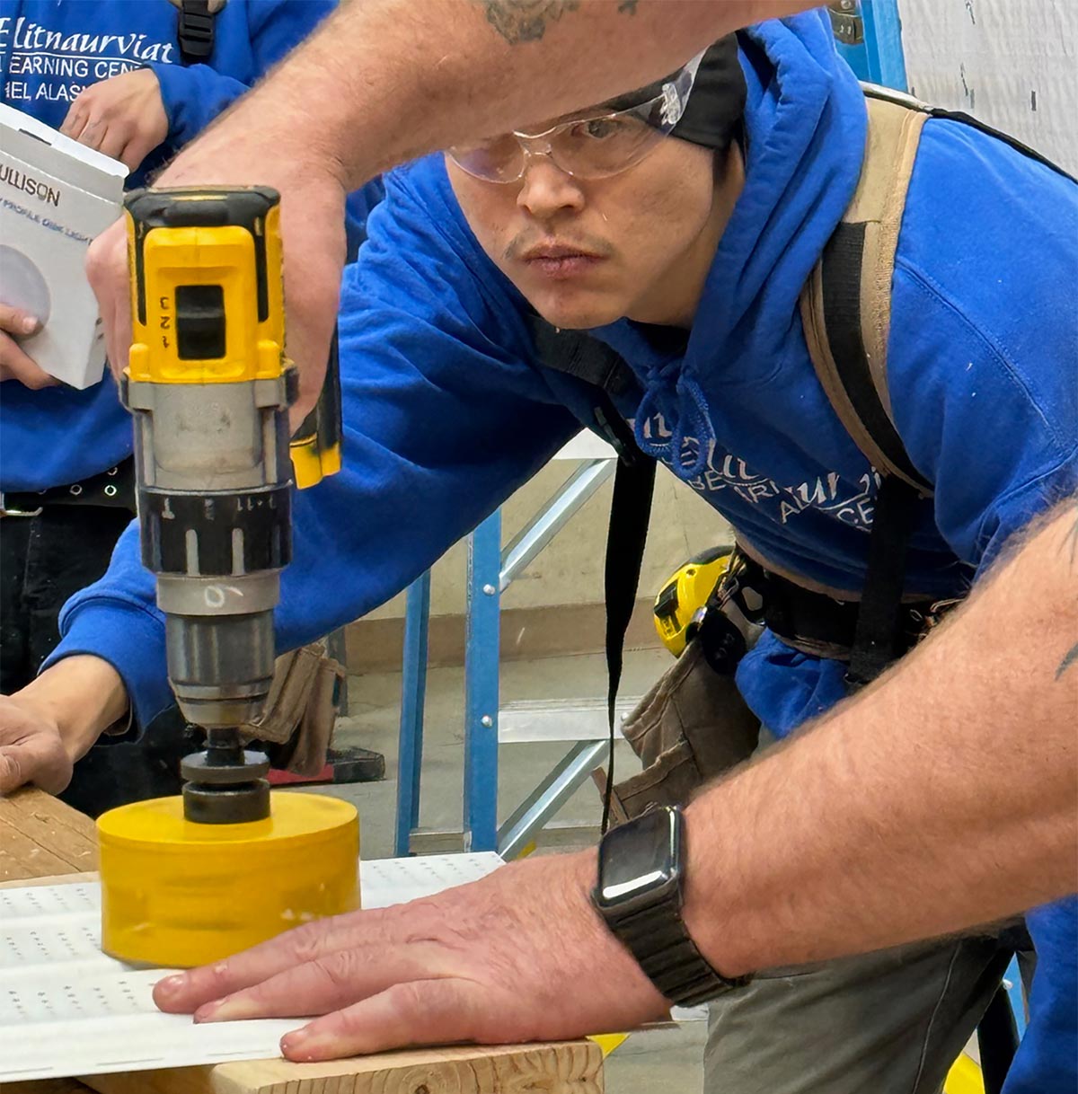 student wearing safety glasses watching a teacher using power tools