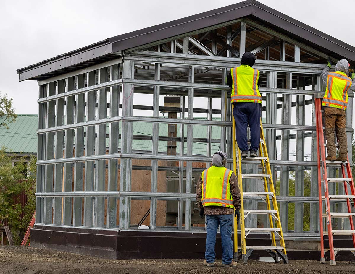 workers wearing safety vests working on a steel house frame