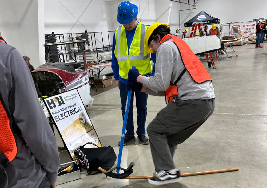 a man overseeing a student using a tool to bend a copper pipe