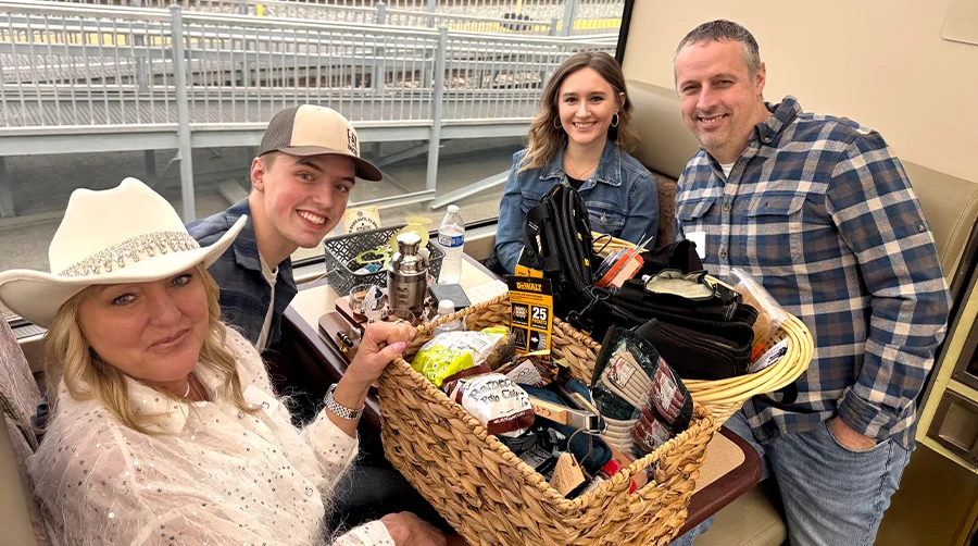four people sitting at a train booth and smiling with baskets of snacks and drinks on the table