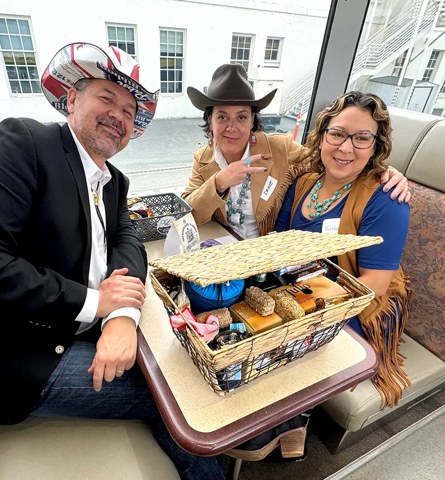 three people sitting at a train booth and smiling with a basket of snacks on the table