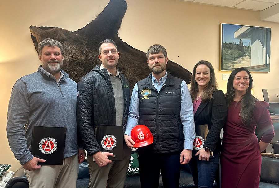 five people in an office holding AGC folders and a hard hat