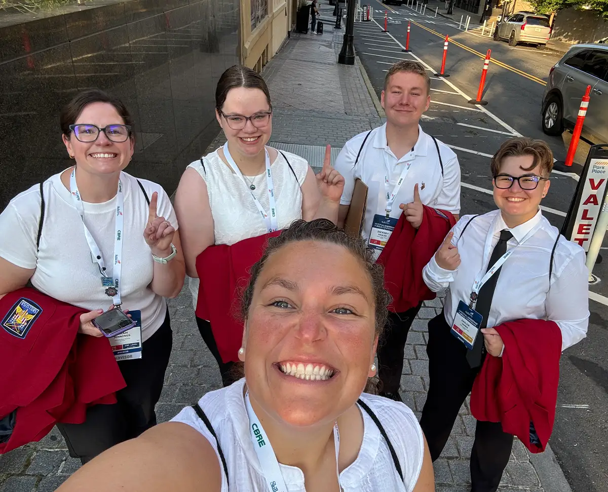 A group of SkillsUSA student leaders and their advisor smiling for a selfie on a city sidewalk during a national conference.