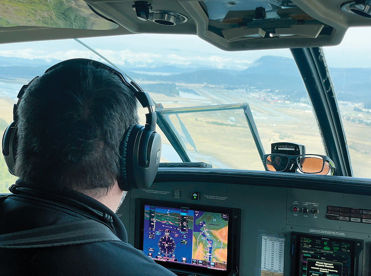View from behind a pilot in the cockpit during an approach to a landing strip.